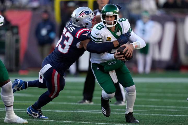 New York Jets quarterback Aaron Rodgers, right, is brought down by New England Patriots linebac ...