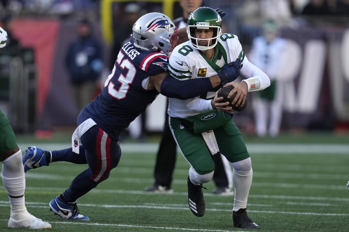 New York Jets quarterback Aaron Rodgers, right, is brought down by New England Patriots linebac ...