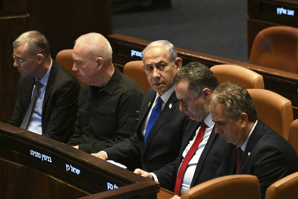 Israeli Prime Minister Benjamin Netanyahu, center, flanked by Defense Minister Yoav Gallant, se ...