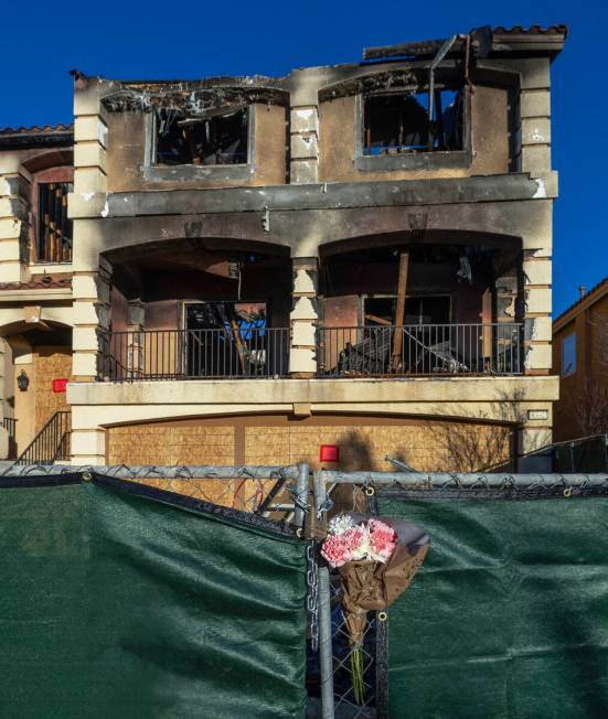 Flowers are placed on emergency fencing around the exterior of fatal house fire at 8332 Langhor ...