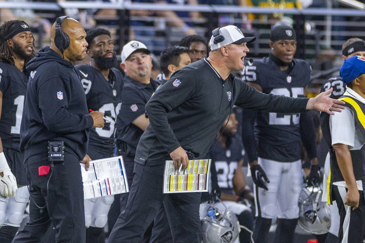 Raiders head coach Antonio Pierce looks on as offensive coordinator Luke Getsy argue flag from ...