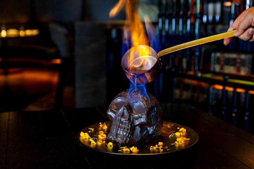 Hot chocolate mocha sauce is poured atop a Diablo Skull en Fuego dessert to reveal flan inside ...