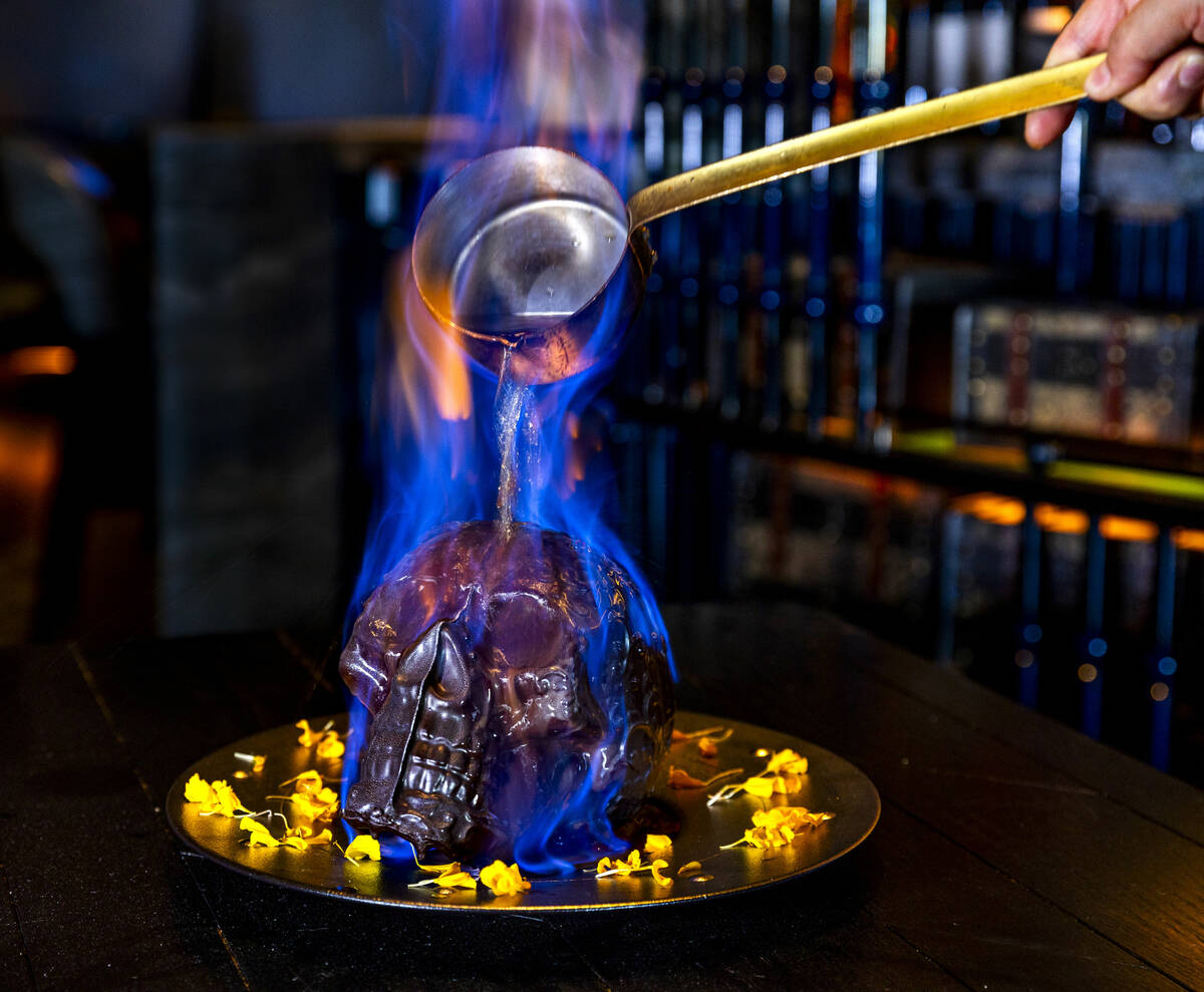 Hot chocolate mocha sauce is poured atop a Diablo Skull en Fuego dessert to reveal flan inside ...