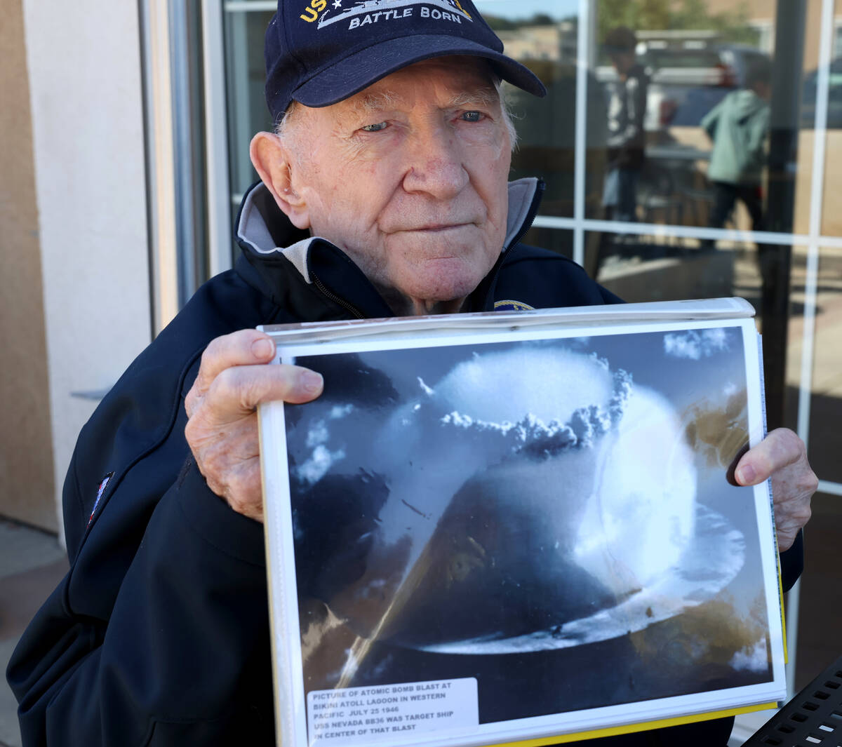 Dick Ramsey, 101, shows a photo of the atomic bomb blast on the USS Nevada during an interview ...