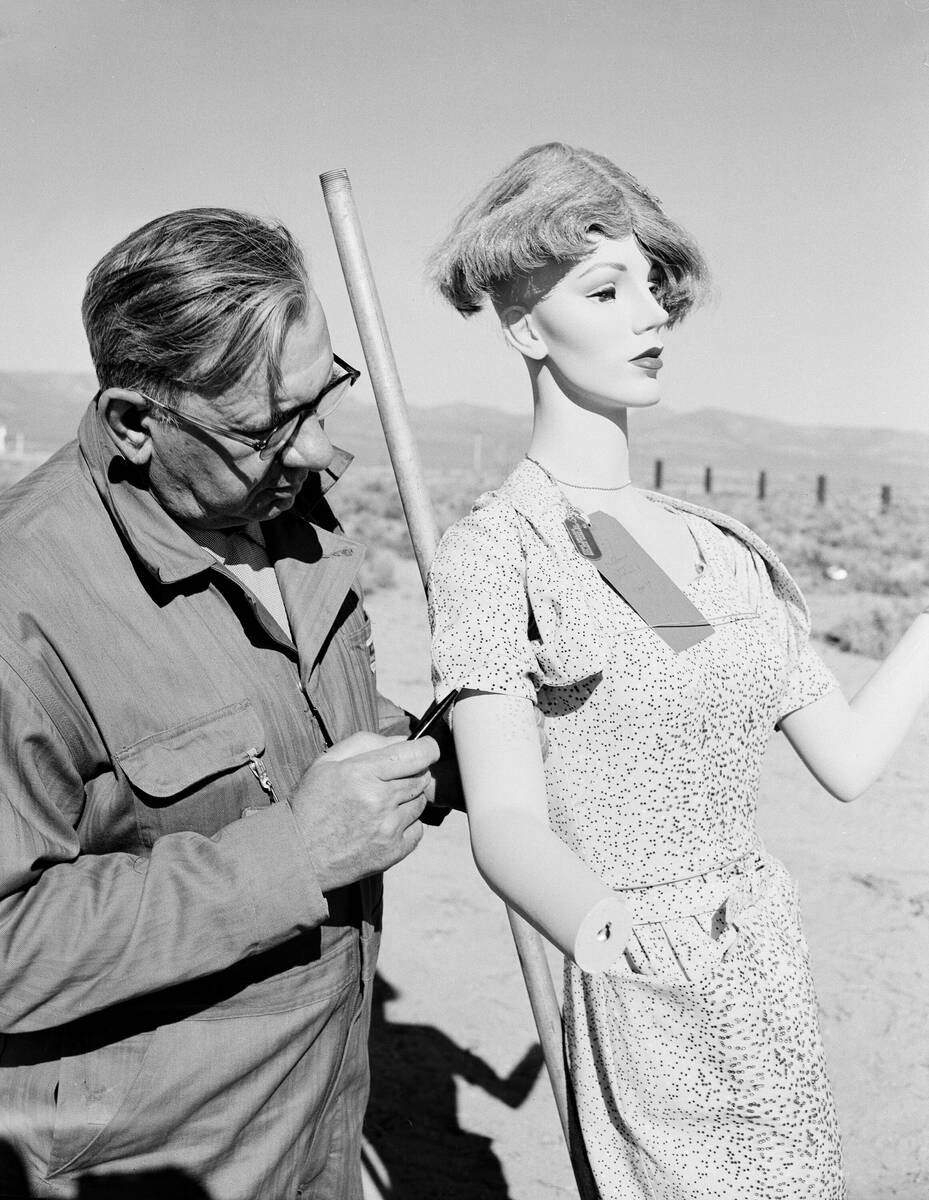 Ray Tiller, chief of the fire department at Waterloo, Ia., examines the dress worn by a mannequ ...