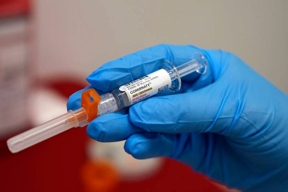 A pharmacist holds a COVID-19 vaccine at a pharmacy in New York, on Tuesday, Sept. 24, 2024. (A ...