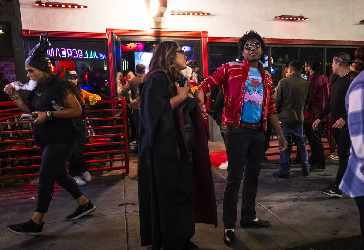 A man dressed as Michael Jackson looks on along Fremont Street during Halloween night on the ea ...