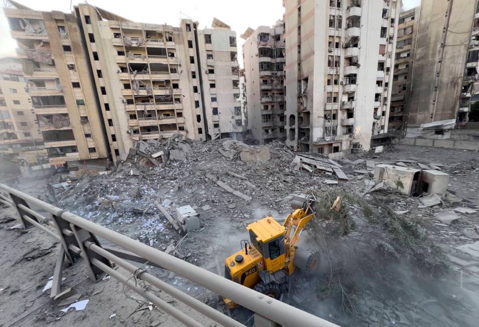 A municipality worker uses a bulldozer to remove the rubble of a destroyed building that was hi ...