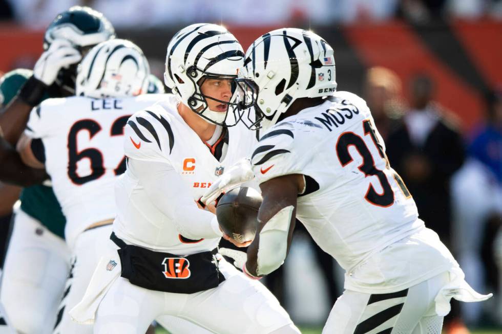 Cincinnati Bengals quarterback Joe Burrow (9) hands off to running back Zack Moss (31) during a ...