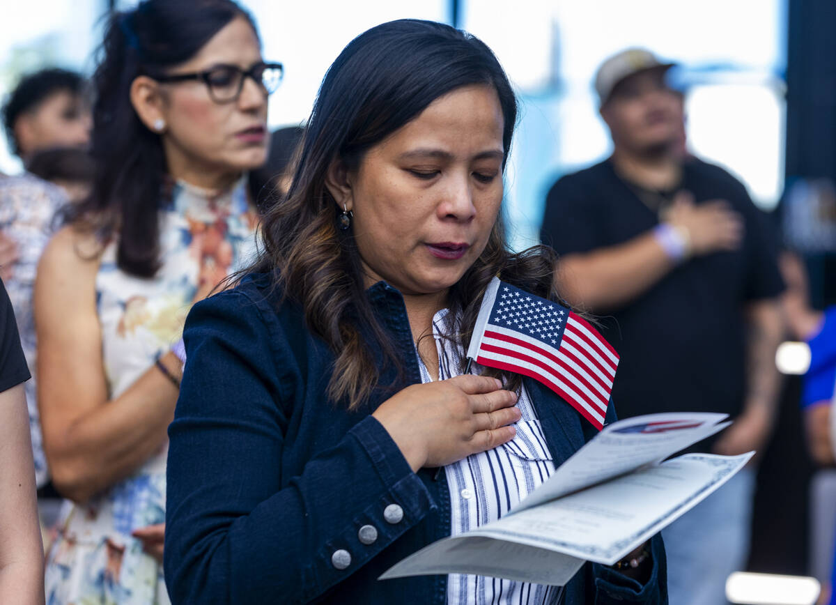 Rosalyn Tuggle stands with others for the Pledge of Allegiance during a naturalization ceremony ...