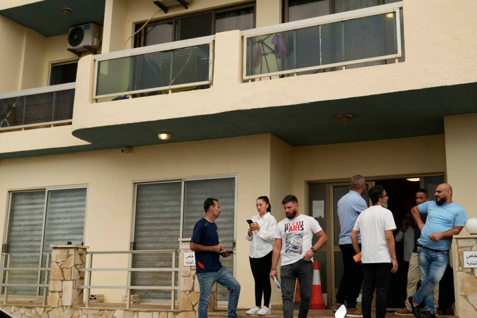 Residents stand at the entrance of a building in Batroun, northern Lebanon, Saturday, Nov. 2, 2 ...