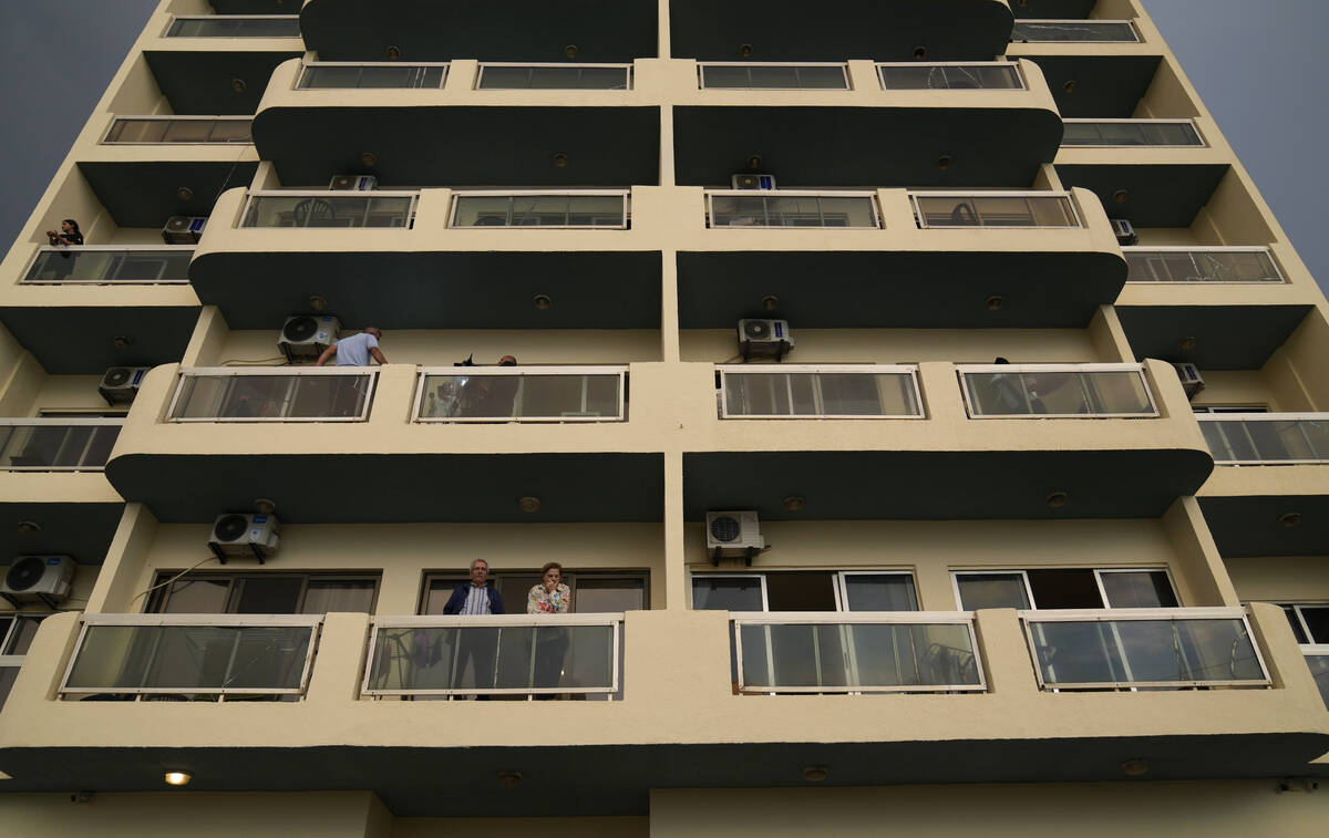 Residents stand on the balcony of a building in Batroun, northern Lebanon, Saturday, Nov. 2, 20 ...