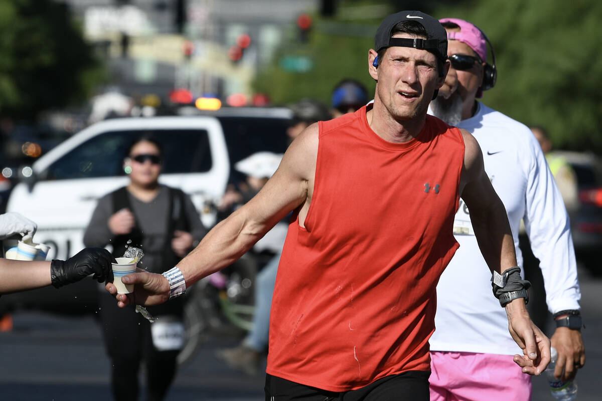 A participant grabs a cup of water during the Las Vegas Marathon Sunday, Nov. 3, 2024, in Las V ...