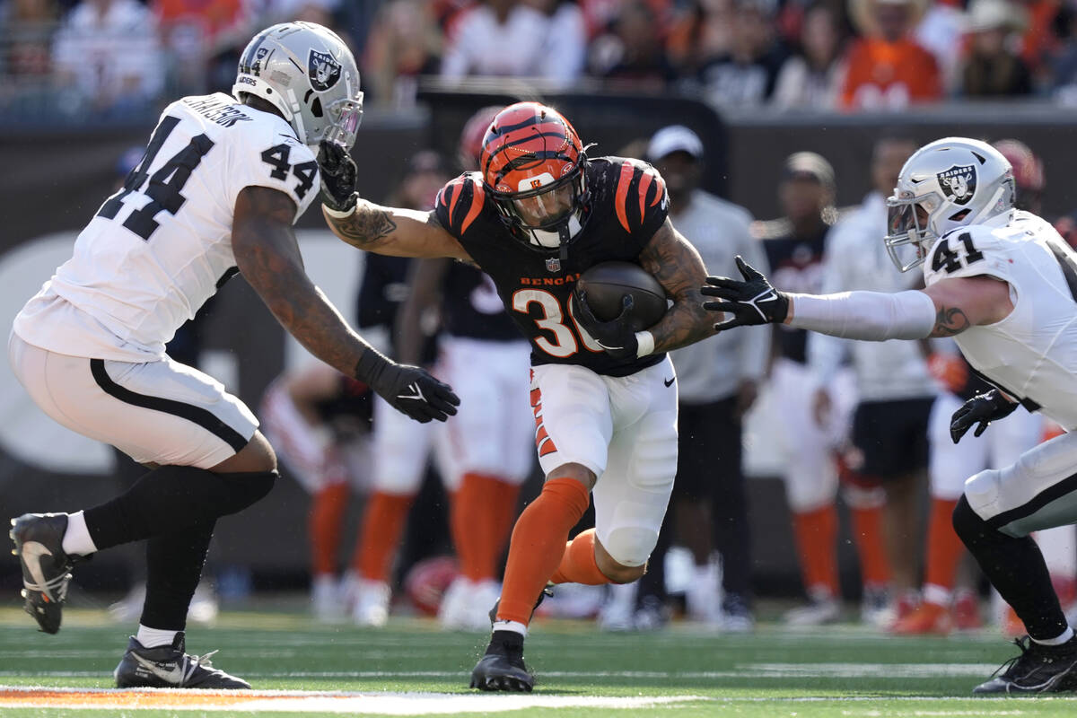 Cincinnati Bengals running back Chase Brown, middle, runs against Las Vegas Raiders defensive e ...