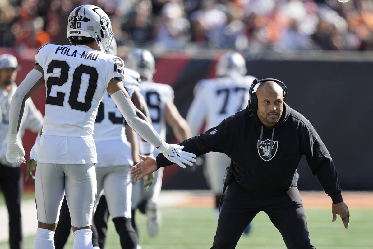 Las Vegas Raiders head coach Antonio Pierce, right, greets safety Isaiah Pola-Mao (20) before a ...