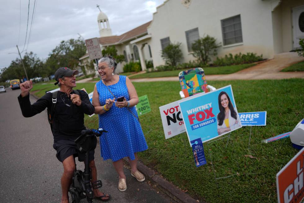 Trump supporter Barney Morin, left, cheers as Democratic poll greeter Lynn Akin helps him find ...