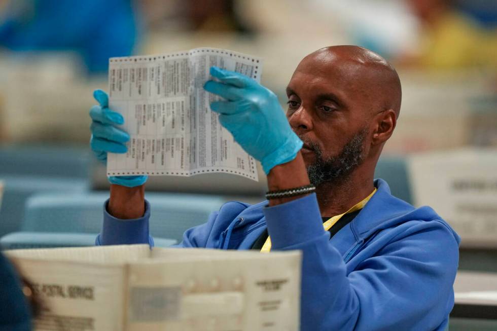 An election worker processes mail-in ballots for the 2024 General Election at the Philadelphia ...