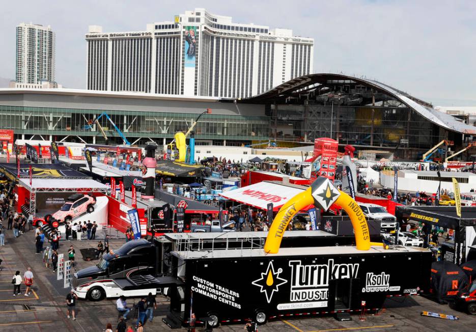 Attendees walk about and view some of the many vehicles on display during the first day of SEMA ...