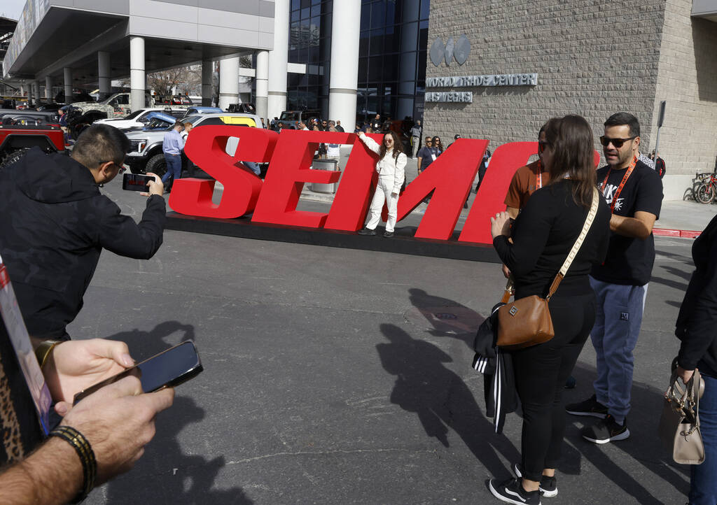 Attendees pose for a photo at a SEMA sign during the first day of SEMA at the Las Vegas Convent ...