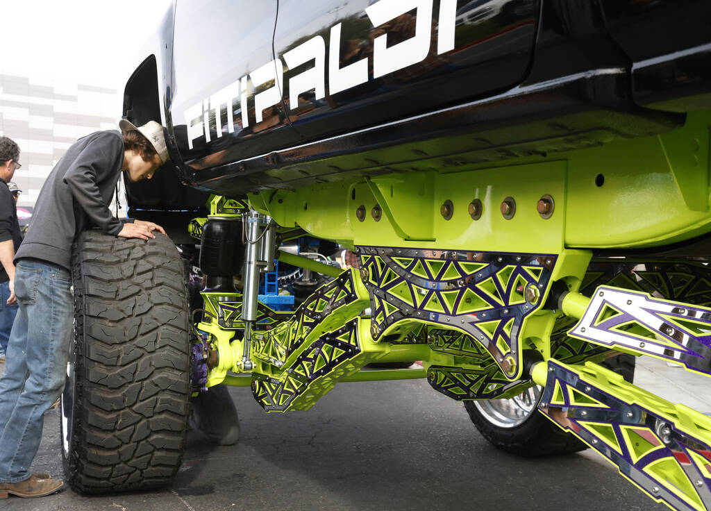 Blake Trench checks his 2016 Chevy Silverado front suspension during the first day of SEMA at t ...