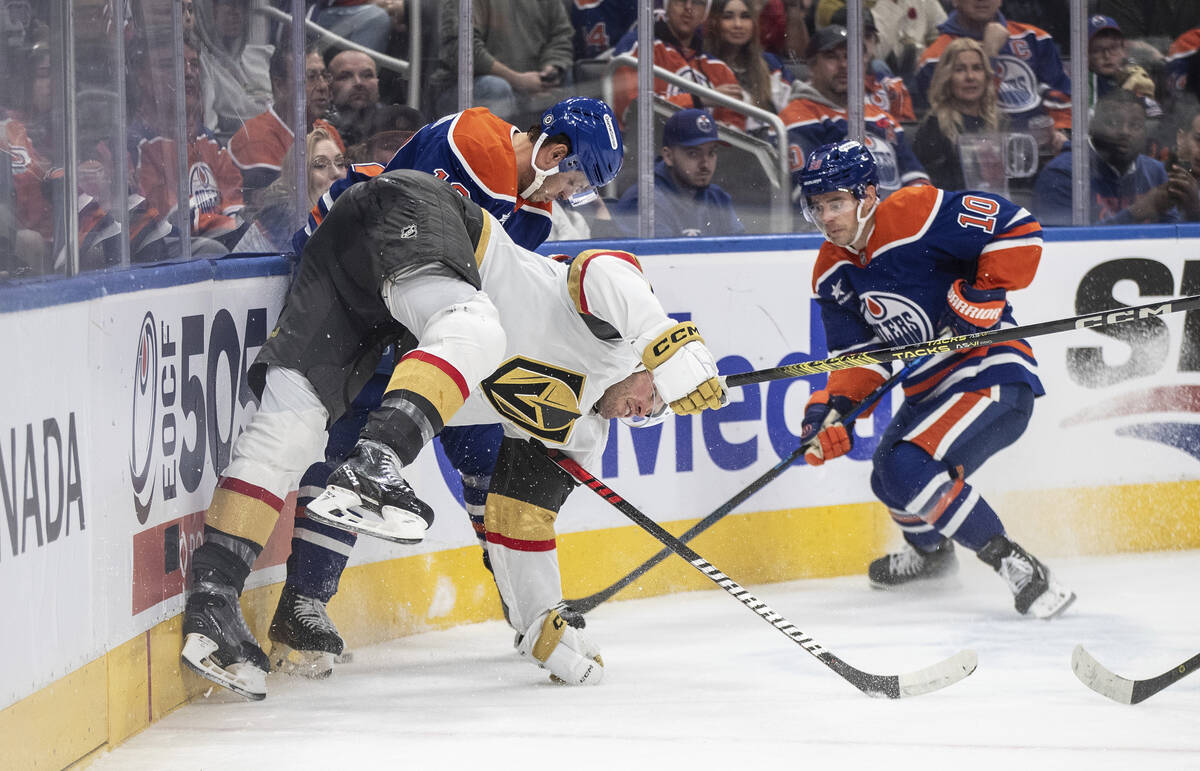 Vegas Golden Knights' Brayden McNabb, front center, is checked by Edmonton Oilers' Mattias Janm ...