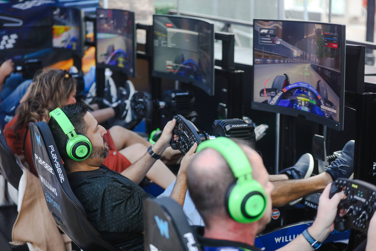 Guests play Formula 1 race video games at the Williams Racing Fanzone, a pop up up for the Las ...