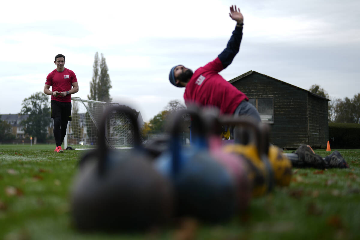 Owner of a personal fitness company Zen Training, Alan Ezen, left, watches his trainer Richard ...