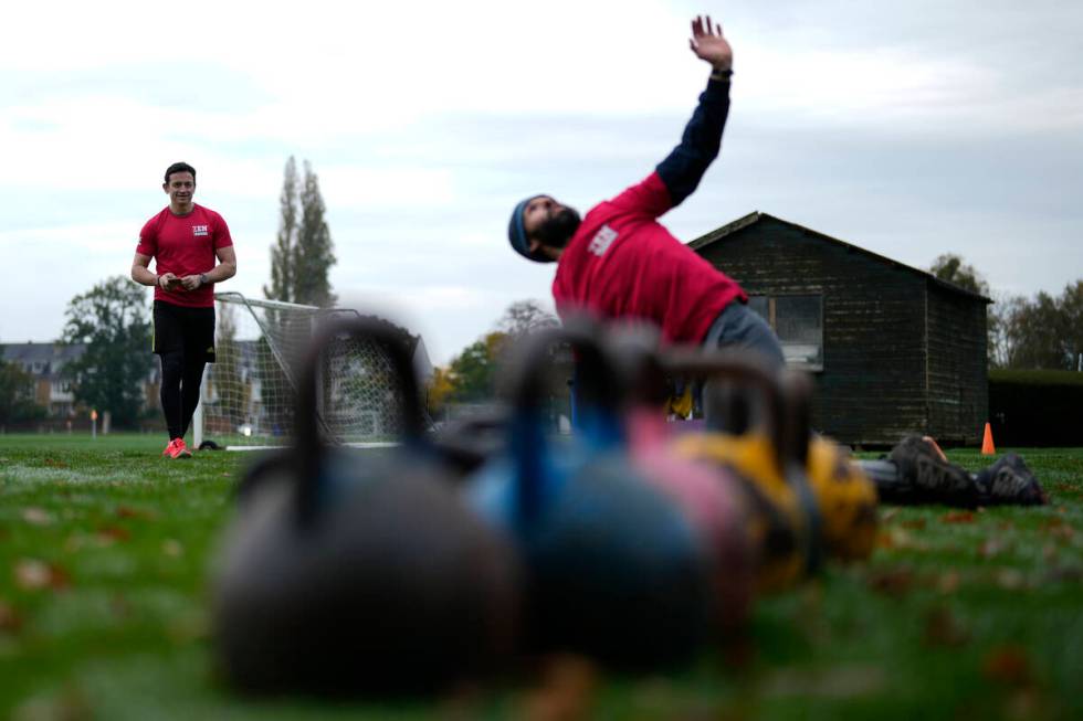 Owner of a personal fitness company Zen Training, Alan Ezen, left, watches his trainer Richard ...