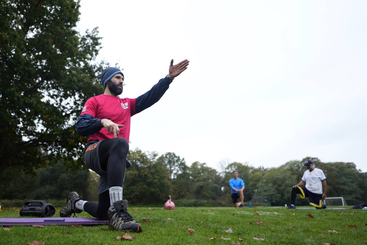 Personal fitness trainer Richard Lamb, gestures as he leads an outdoor gym class in London, Sat ...