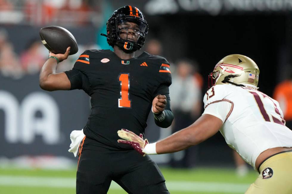 Miami quarterback Cam Ward (1) looks to pass as Florida State defensive lineman Sione Lolohea ( ...