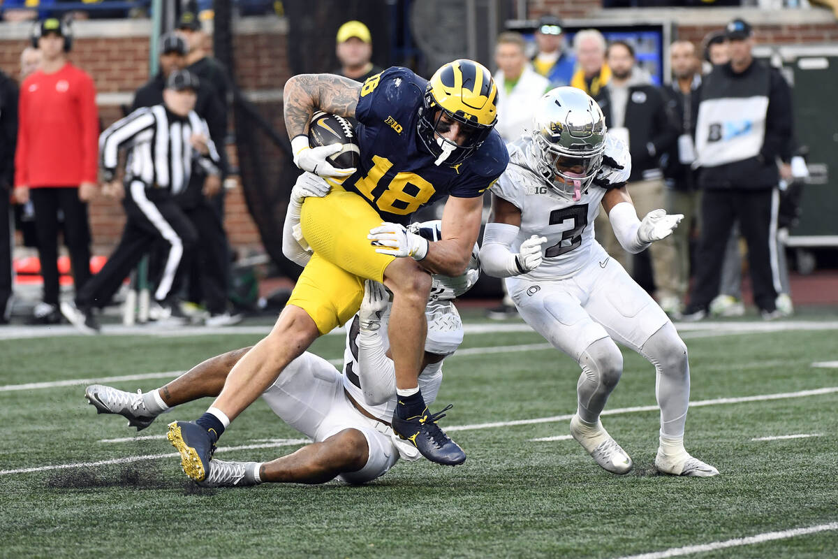 Michigan tight end Colston Loveland (18) runs after making a catch and is tackled by Oregon def ...