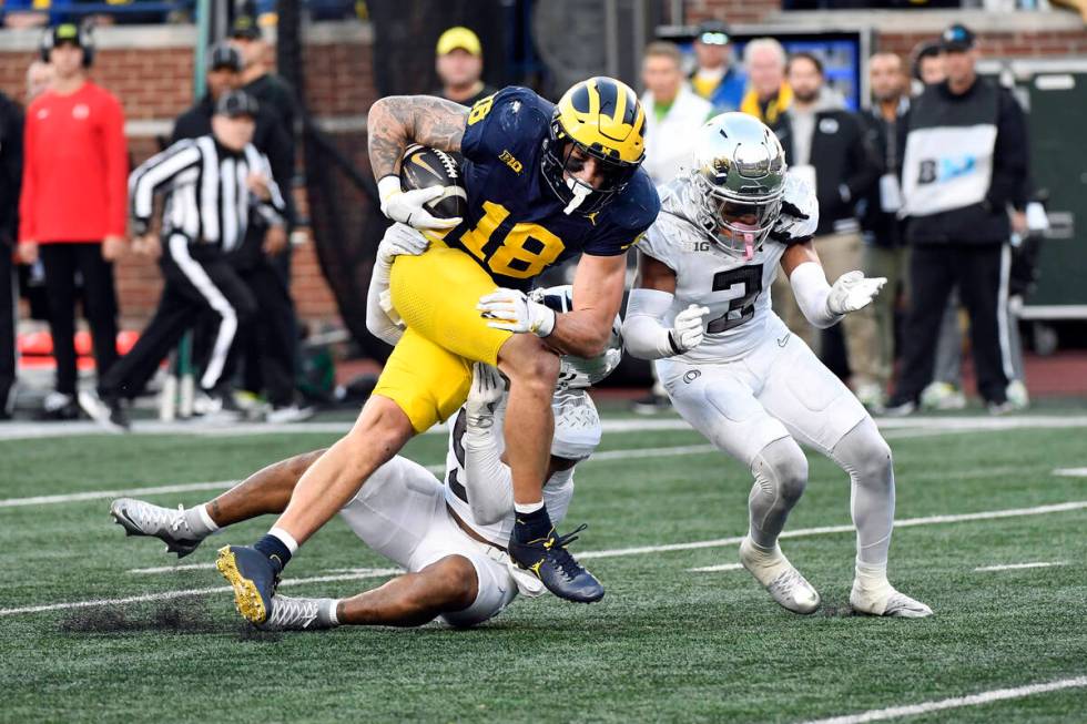 Michigan tight end Colston Loveland (18) runs after making a catch and is tackled by Oregon def ...