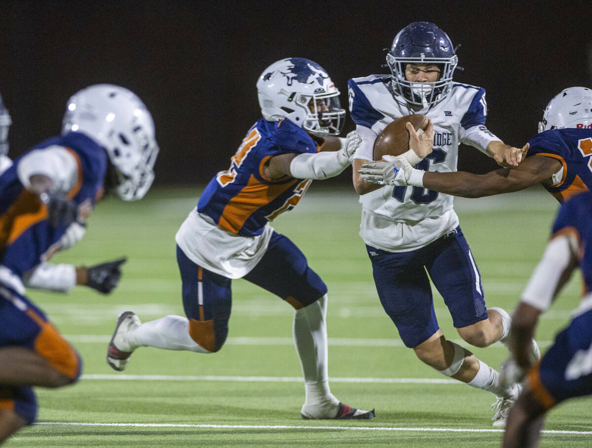 Shadow Ridge quarterback Gage Crnkovic (16) works to break a grab by Legacy middle linebacker M ...