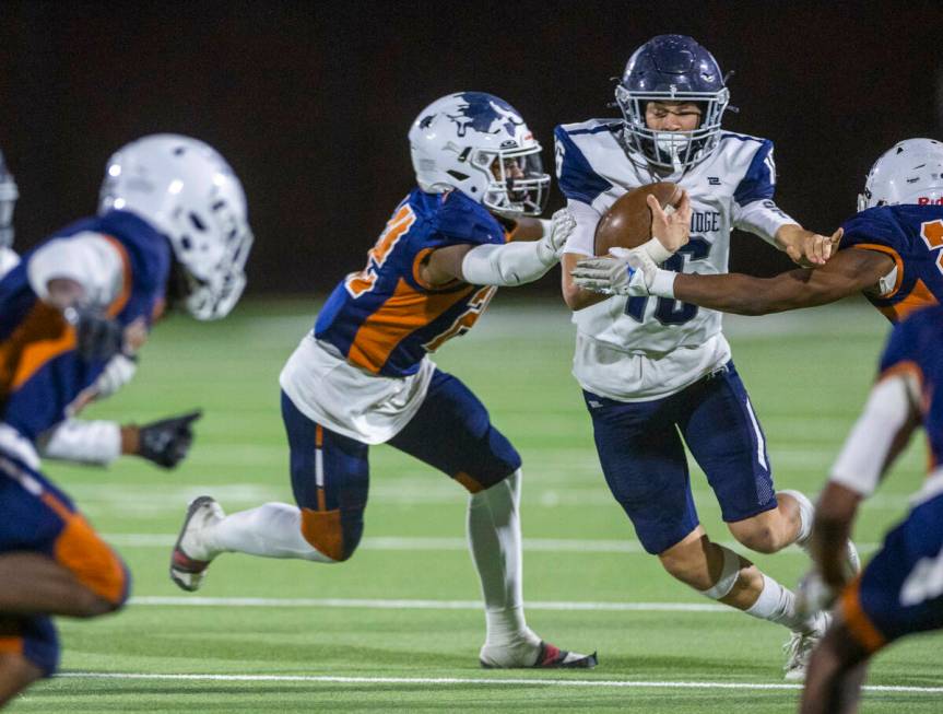 Shadow Ridge quarterback Gage Crnkovic (16) works to break a grab by Legacy middle linebacker M ...