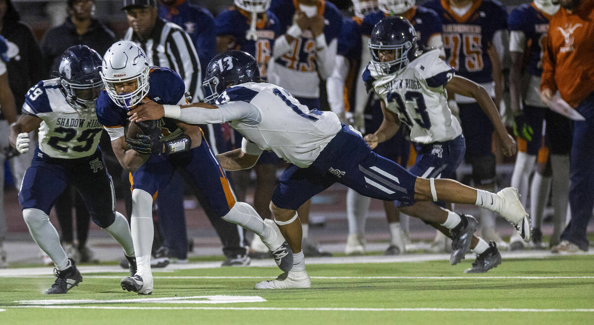 Legacy halfback Zaione Henderson (5) secures a catch as Shadow Ridge defensive end Malahkai Ber ...