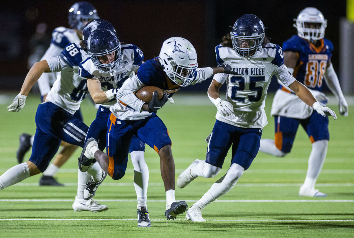 Legacy halfback Zaione Henderson (5) is grabbed from behind by Shadow Ridge safety Hawkin Ledin ...