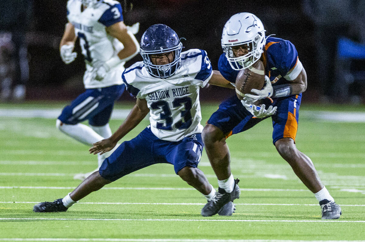 Legacy wide receiver Dominic Oliver (1) secures a catch as Shadow Ridge safety Mujahid Gilliard ...