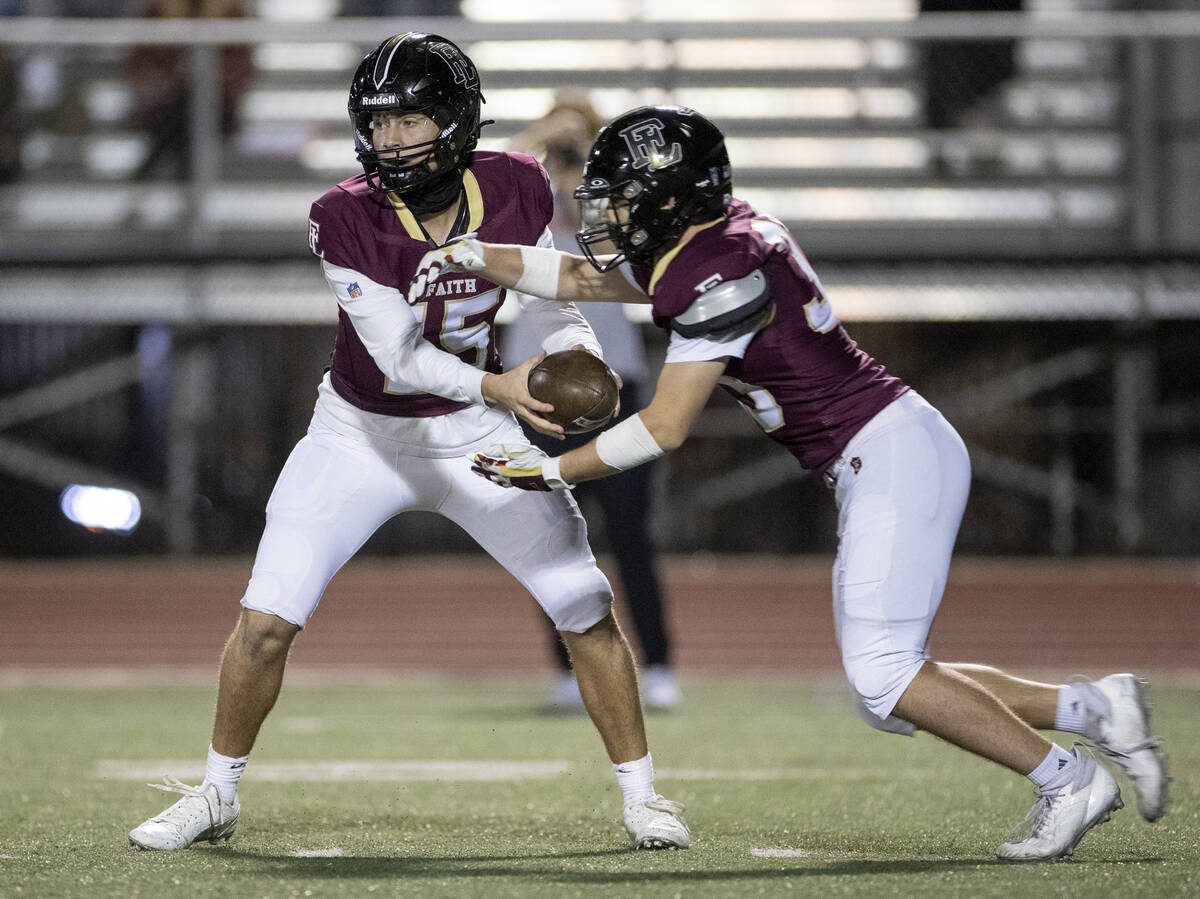 Faith Lutheran senior Alexander Rogers (15) hands the ball to junior Justin Robbins (33) during ...