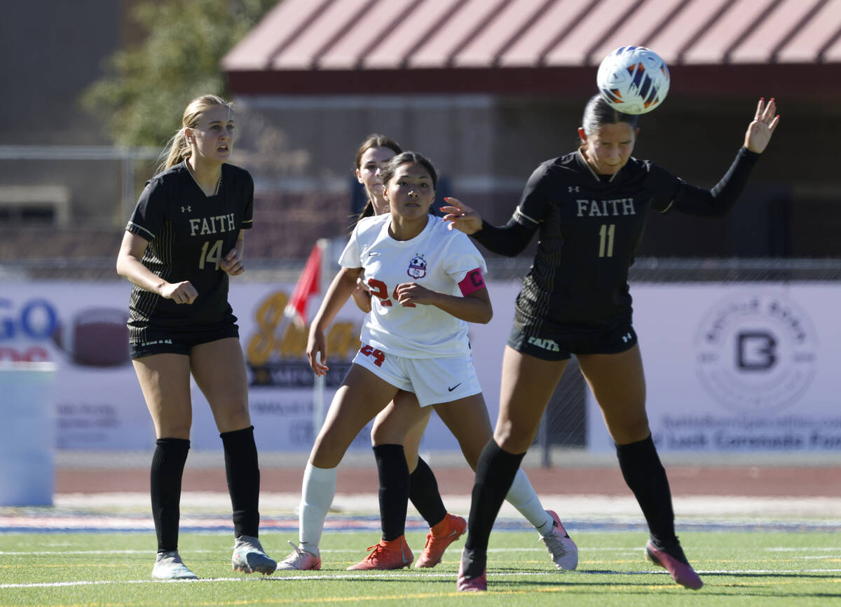 Faith Lutheran's midfielder Ana Coe (11) goes for a header as she defends against Coronado High ...