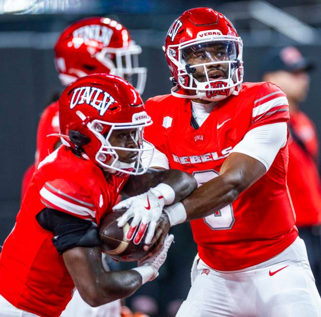 UNLV quarterback Hajj-Malik Williams (6) hands the ball to running back Jai'Den Thomas (9) duri ...