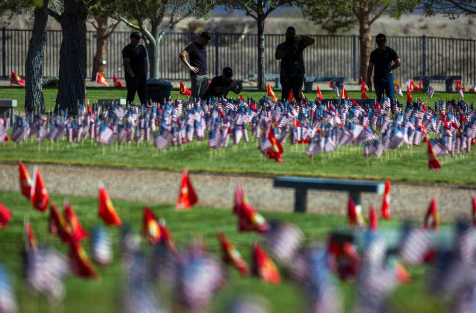 Visitors take in some of around 14,000 small American flags at veterans grave markers in the So ...