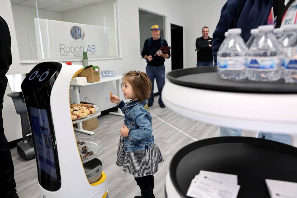 Zoey Zozaya, 3, of Henderson interacts with robots delivering refreshments during the grand ope ...