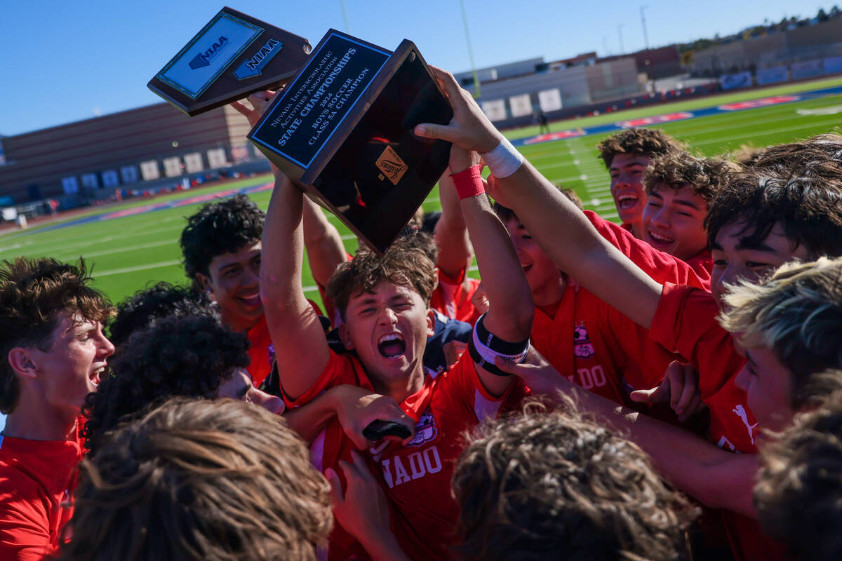 The Coronado boys soccer team, including Austin Kiernan with trophy, celebrates during a 5A boy ...