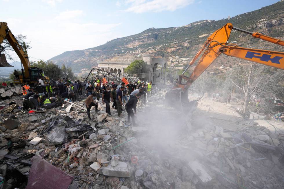 Rescue workers use excavators to remove the rubble of a destroyed house hit in an Israeli airst ...