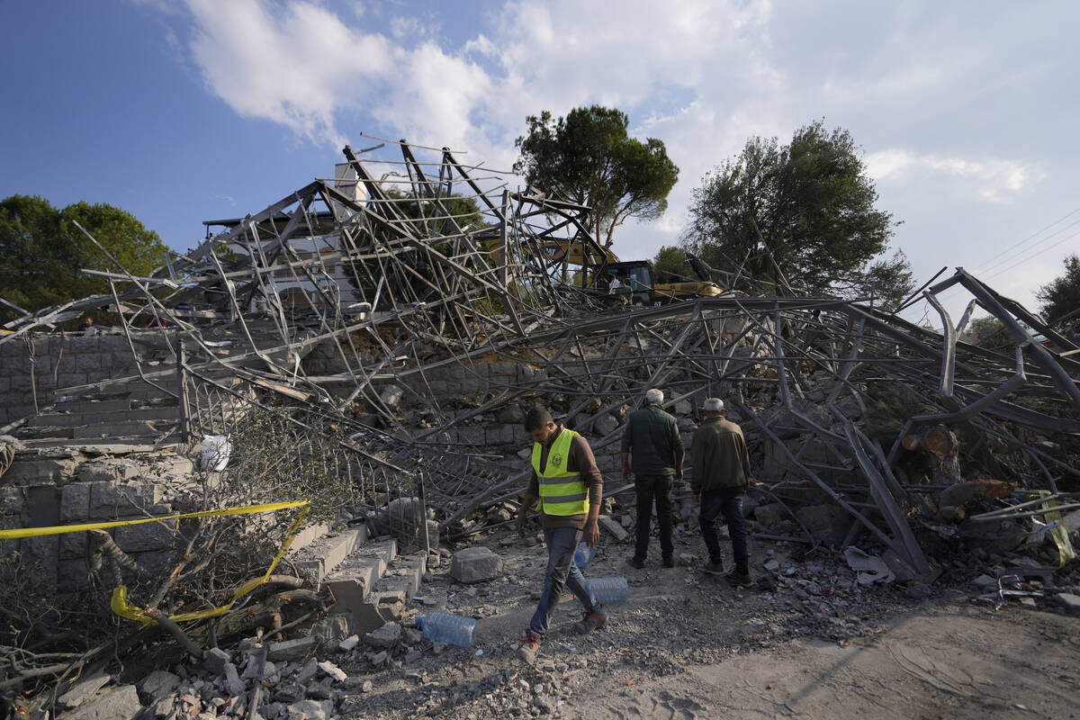 People and a rescue worker gather at the site where an Israeli airstrike hit a house in Aalmat ...