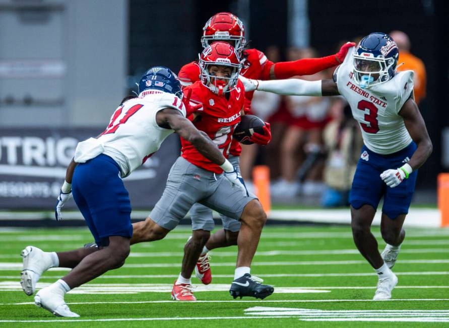 UNLV wide receiver Jacob De Jesus (21) looks to stiff arm Fresno State Bulldogs defensive back ...