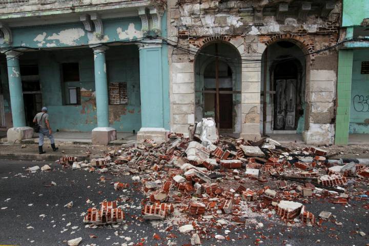 Debris from a building damaged by the passage of Hurricane Rafael covers the street in Havana, ...