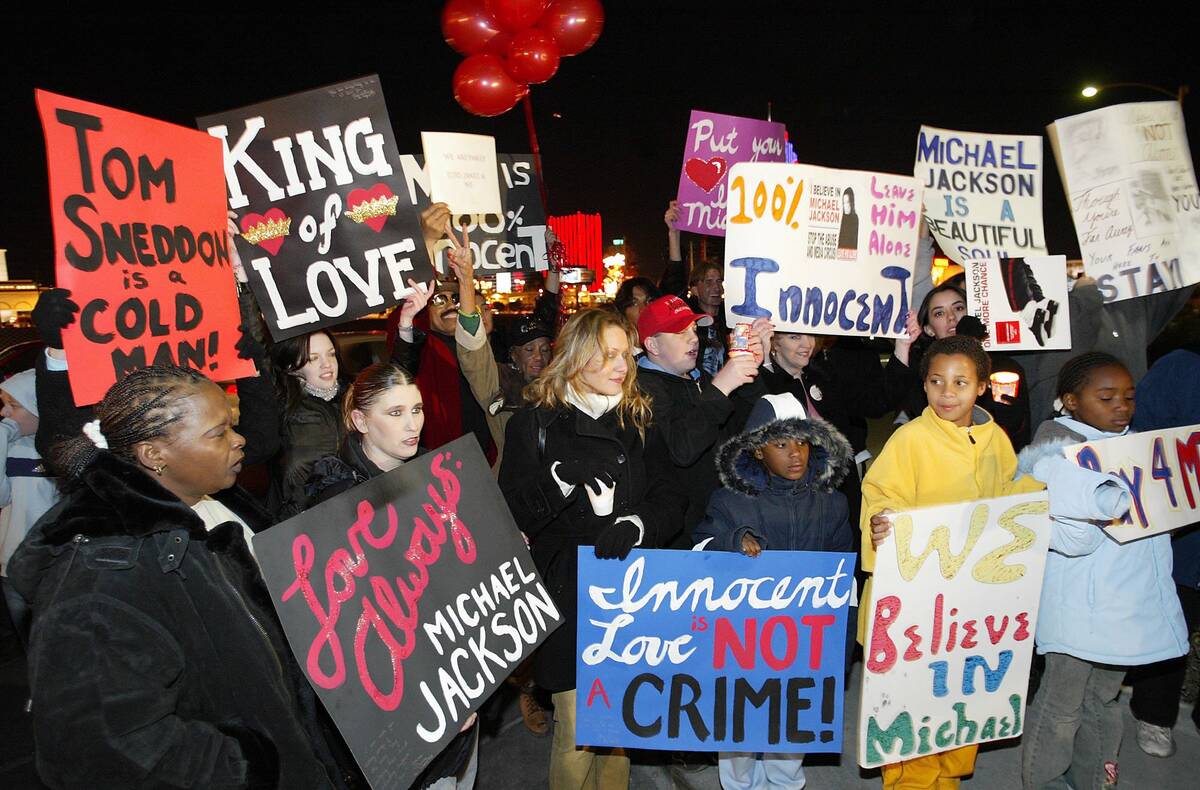 A small crowd of people hold up signs outside of the Las Vegas studio where Michael Jackson had ...