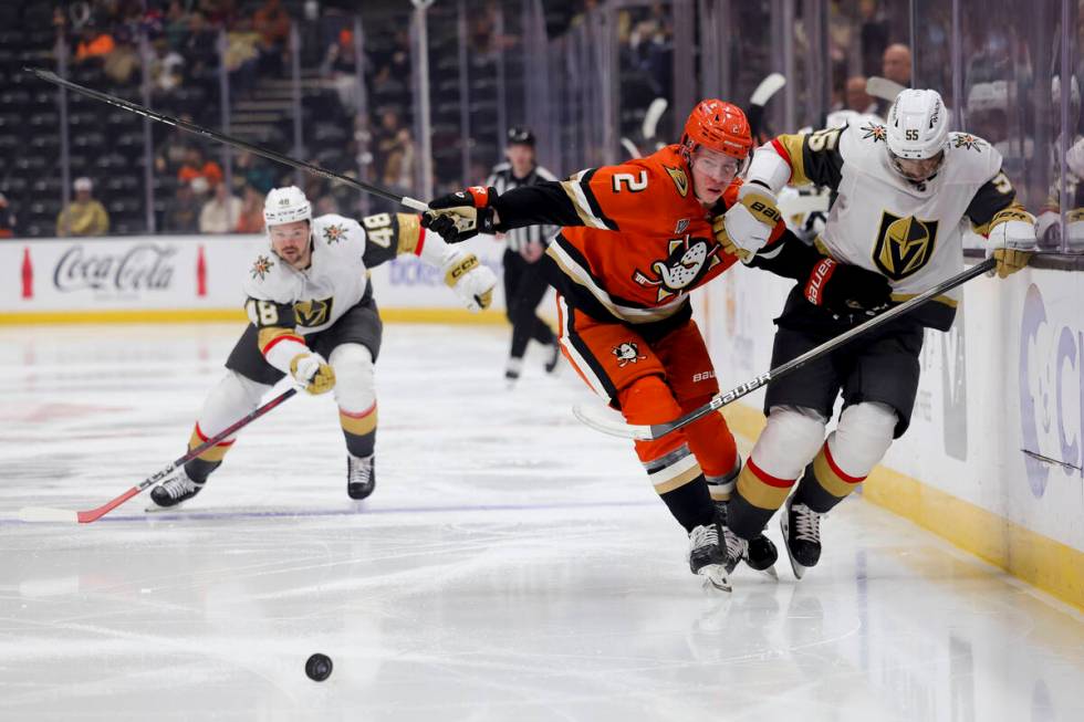 Anaheim Ducks defenseman Jackson LaCombe, center, and Vegas Golden Knights right wing Keegan Ko ...