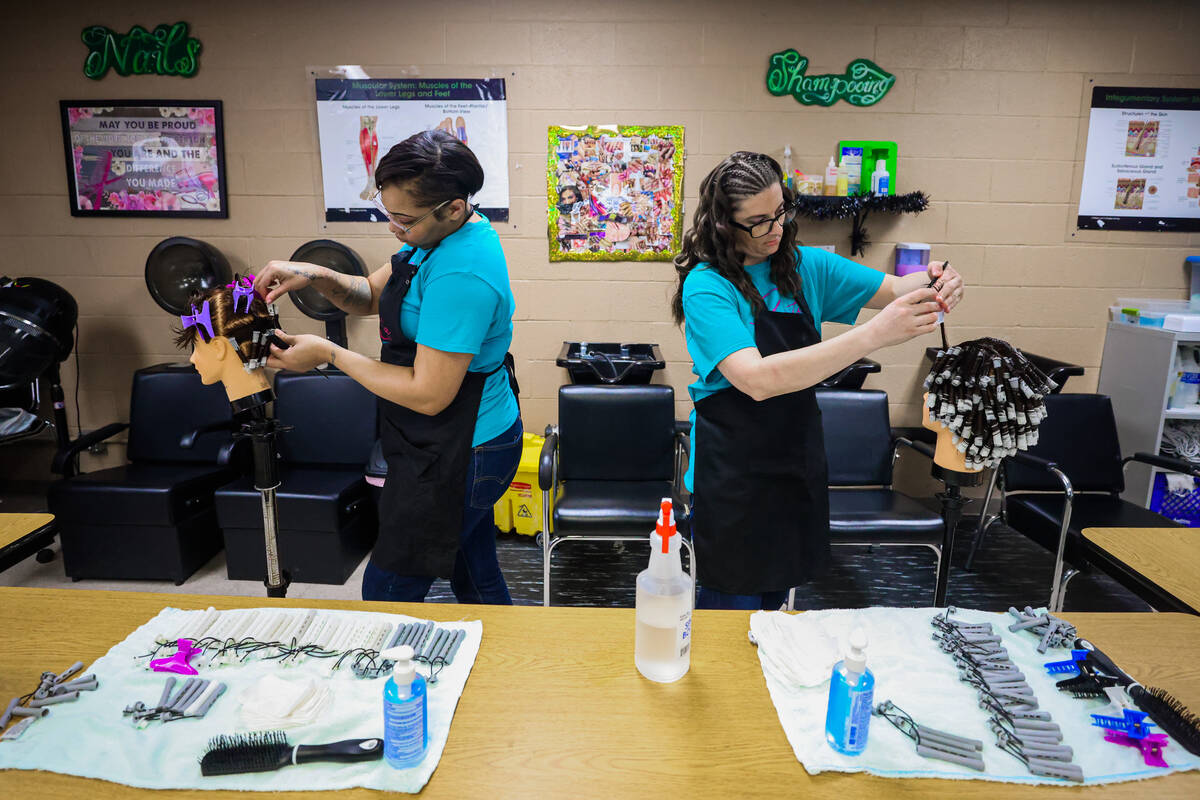 Lishae Macfield, left, and Marlee Mathews practice perms on mannequins during a cosmetology cla ...